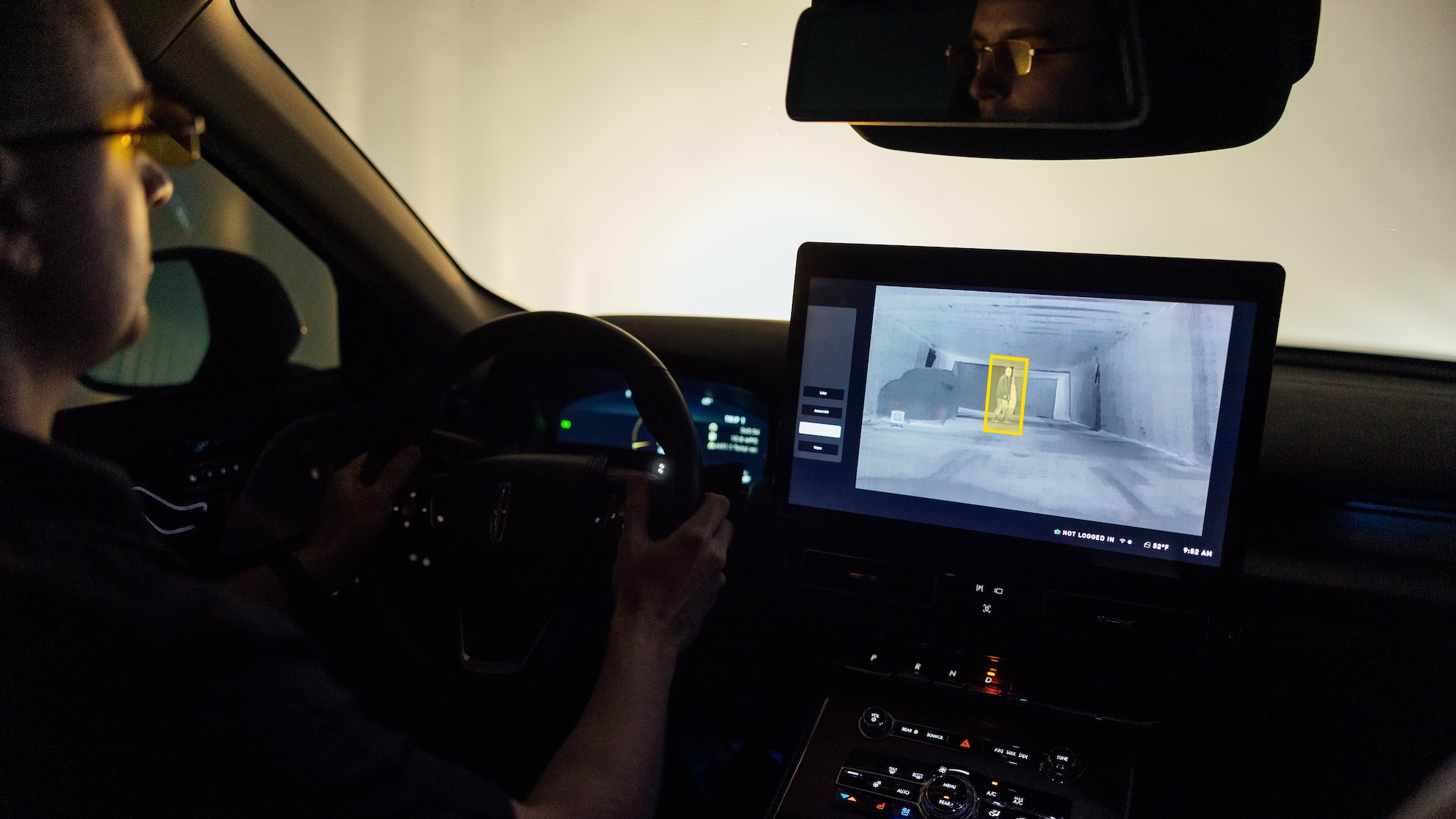 person driving car with screen showing thermal vision on dashboard