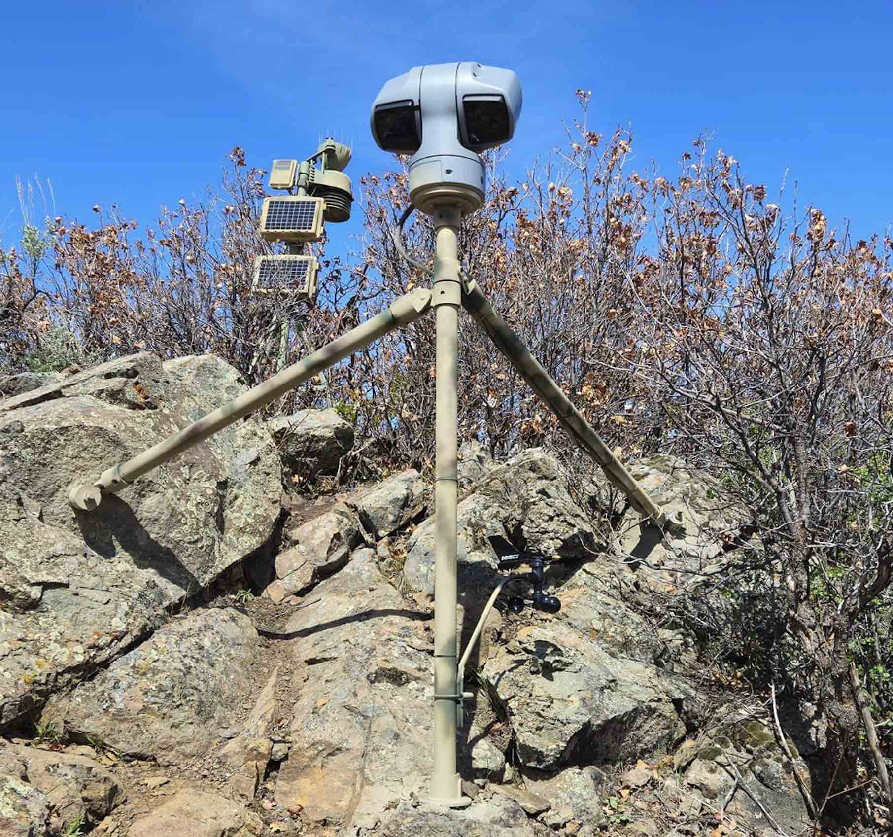 a weather station mounted on a tripod and embedded in rock in colorado