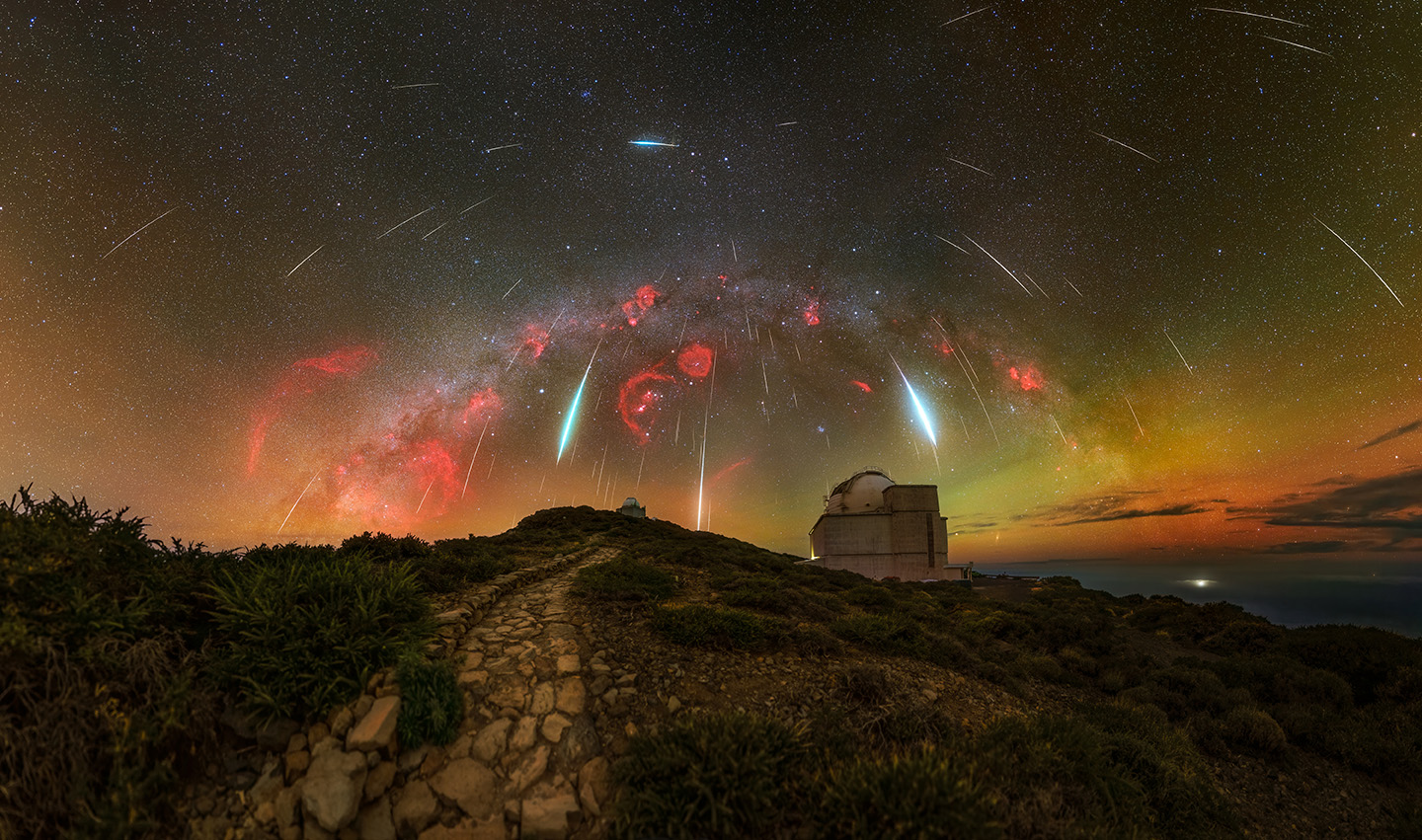 Meteors look like rain with bursts of red light seen above a building 