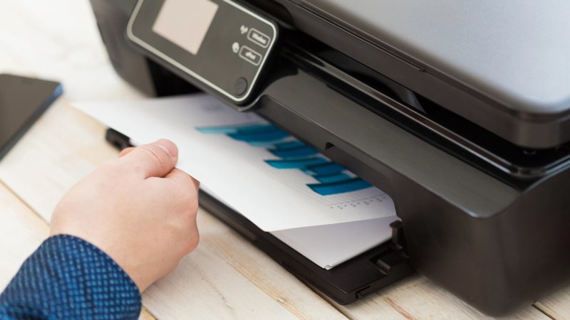 Man's hand reaching for printer paper