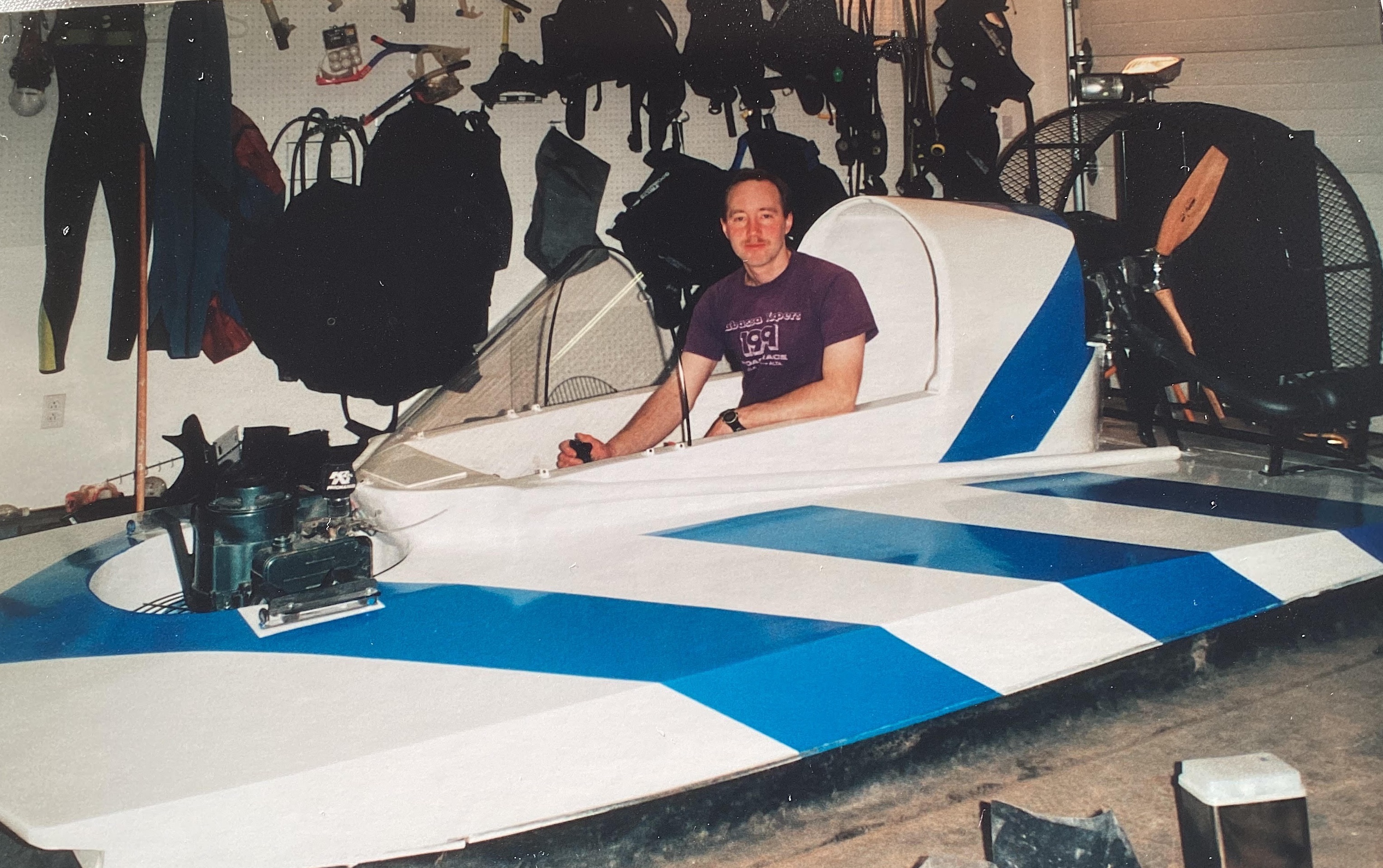 a man sits in a white and blue hovercraft 