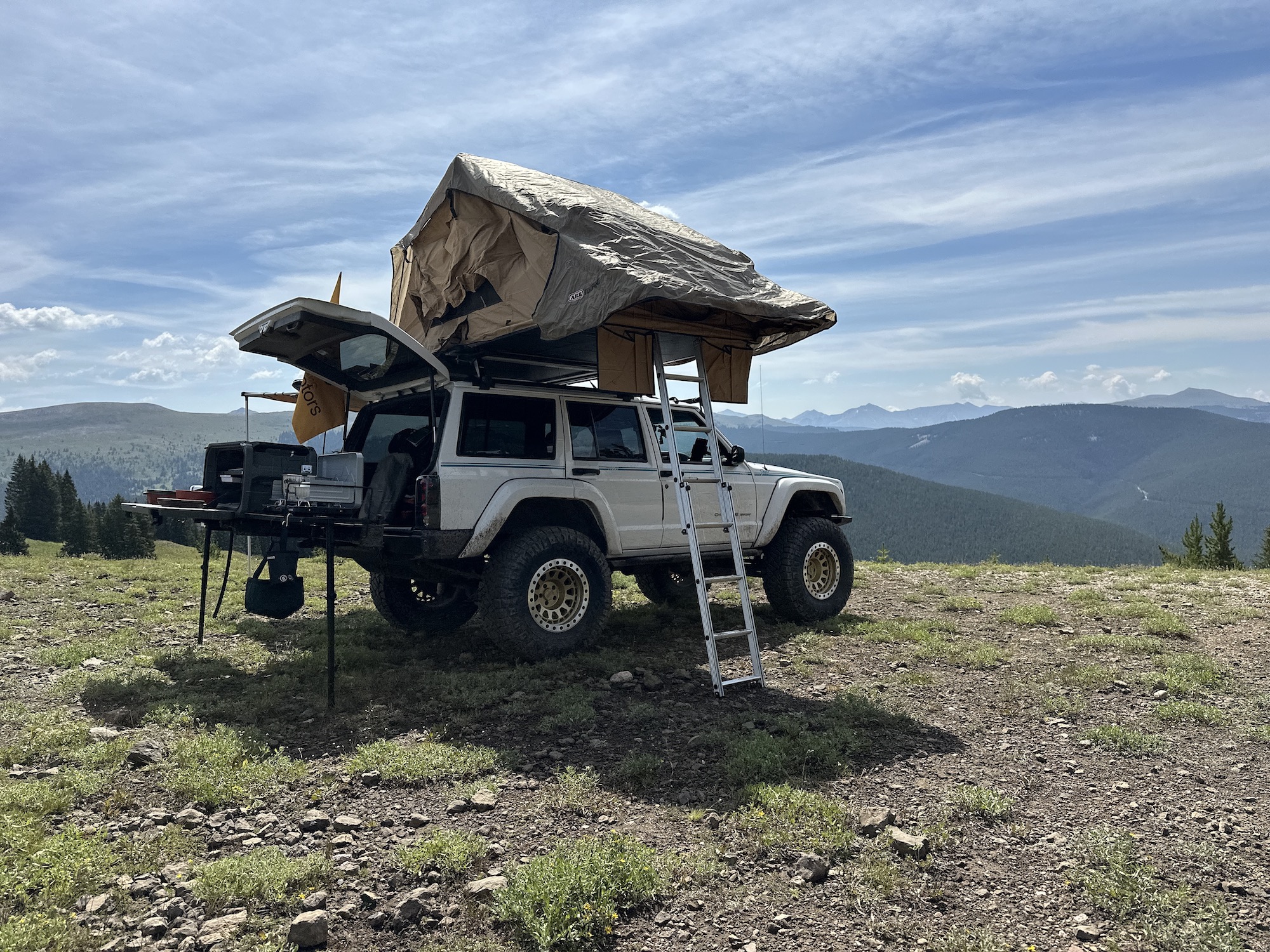 white jeep with tent on roof and grill set up off the back truck