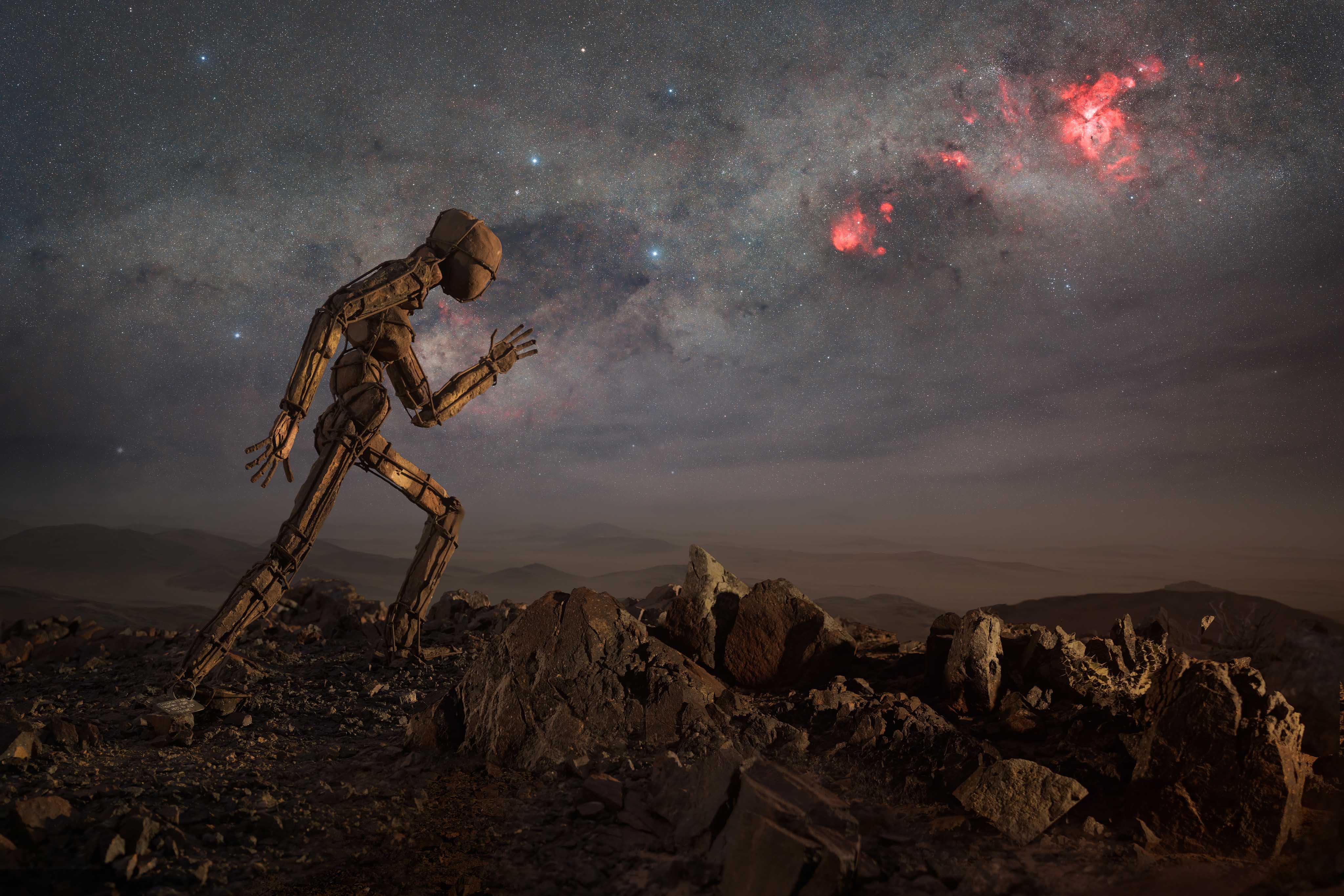 a statue of a person walking under the milky way