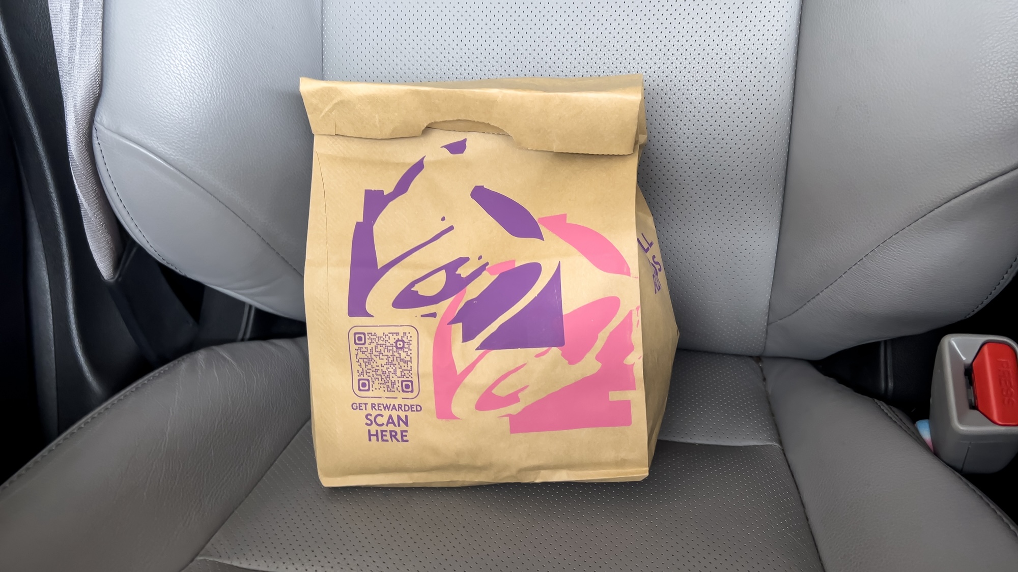 Close up view of a Taco Bell fast food bag inside of a car.