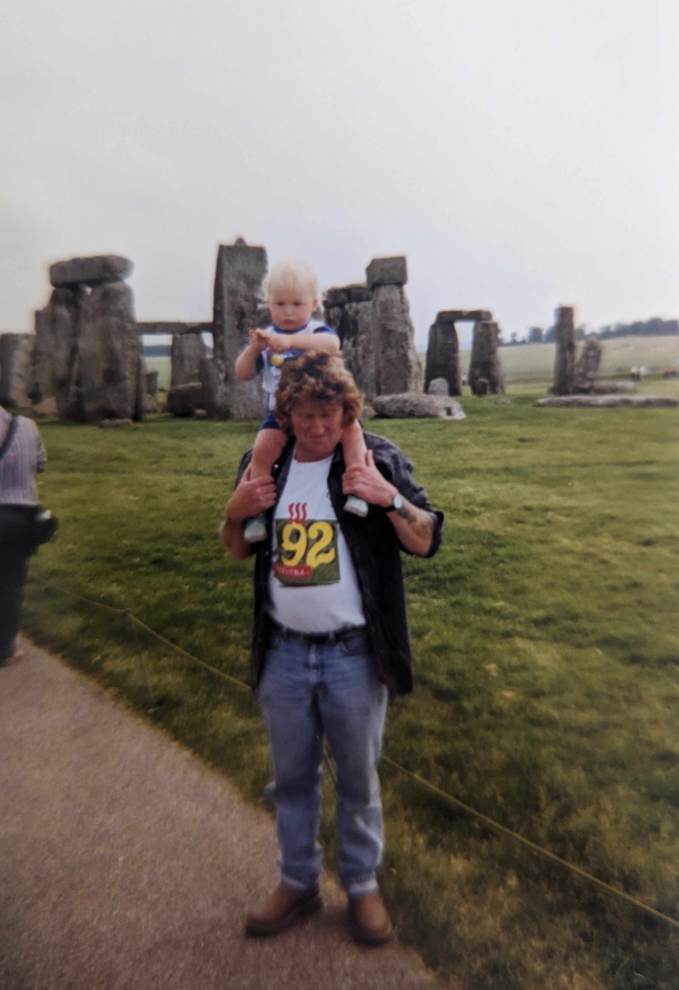 a young boy on his father's shoulders in front of stonehenge in 1998. 