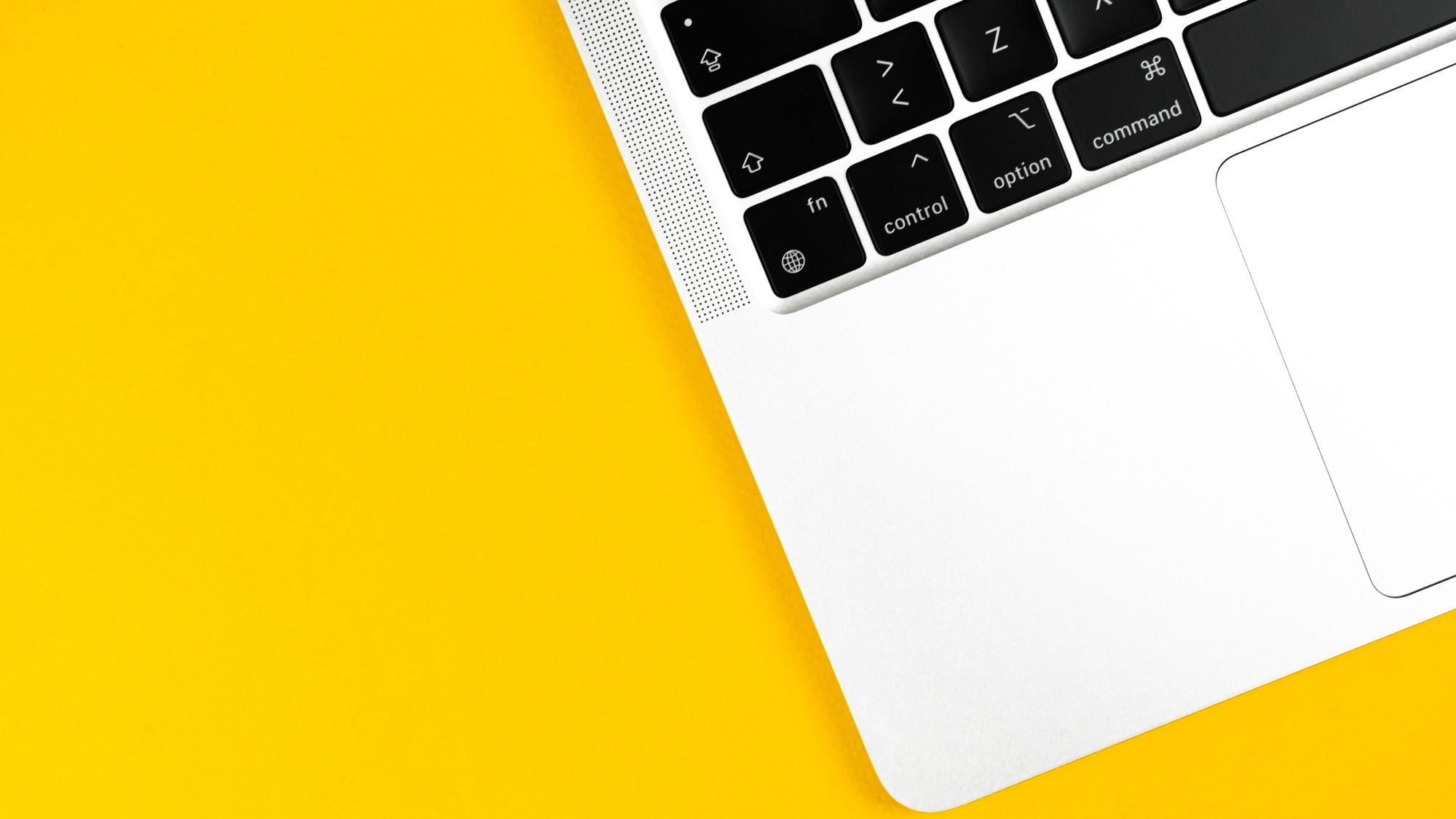 Modern laptop flat lay yellow background.