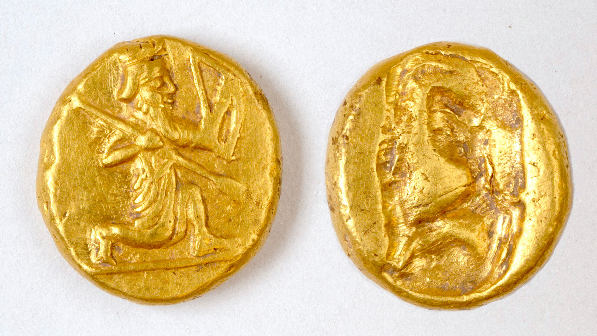 two ancient gold coins with the image of an archer carved into them