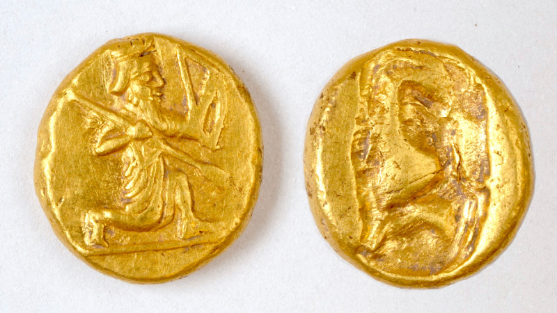 two ancient gold coins with the image of an archer carved into them