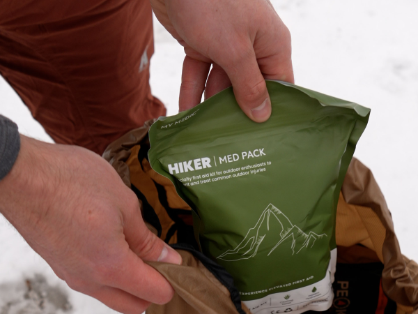 A hiker grabbing a medical pack out of their backpack.