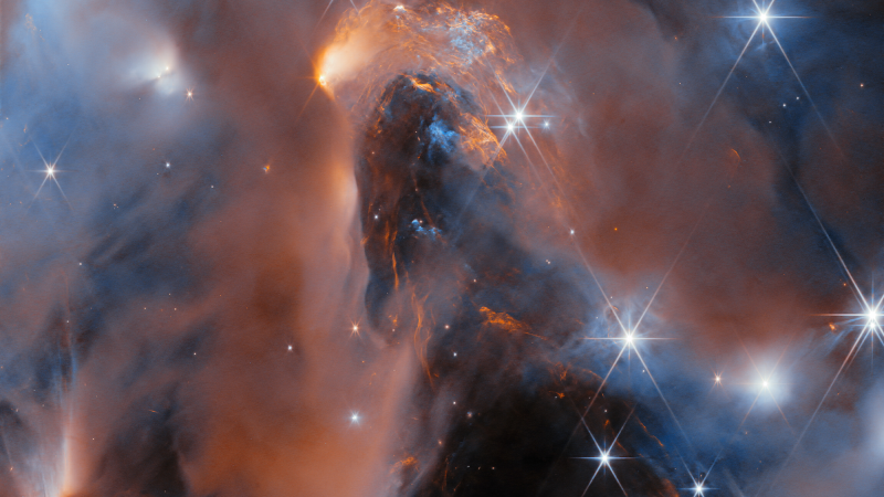 a space telescope image of multiple shining stars in reddish clouds