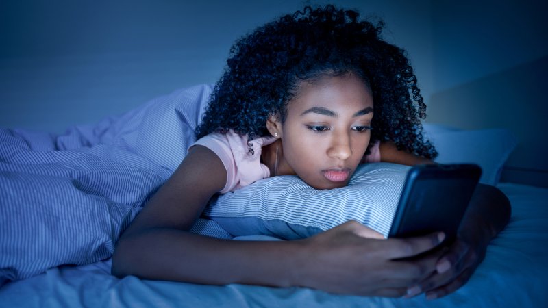 young girl using phone at night in bed