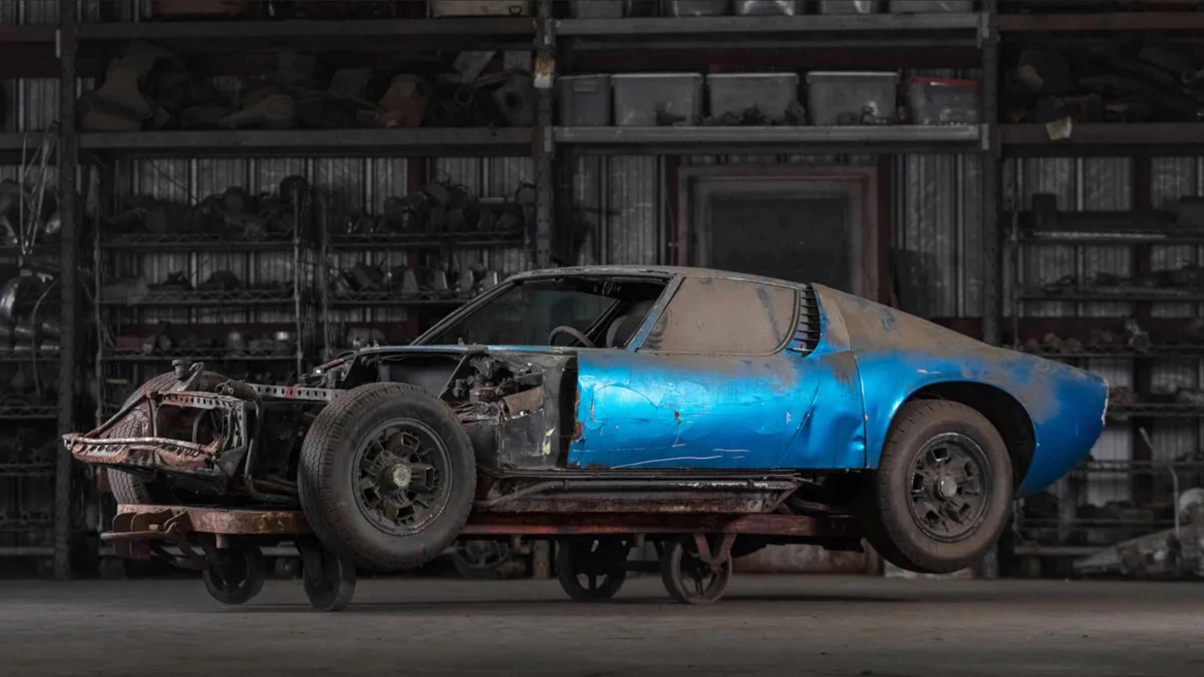 blue supercar with hood missing, exposing engine block. covered in dust