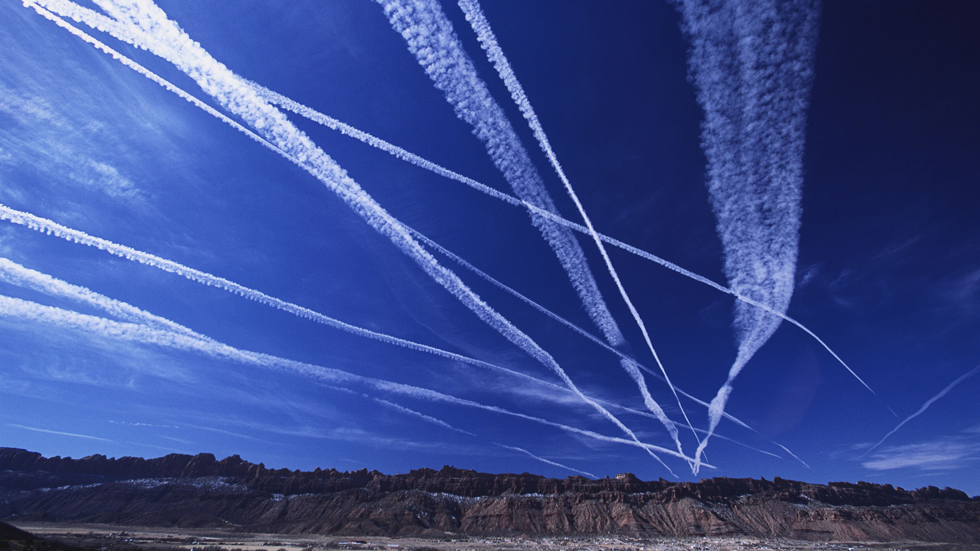 Contrail clouds from passing jet planes streak the sky over the Utah desert.