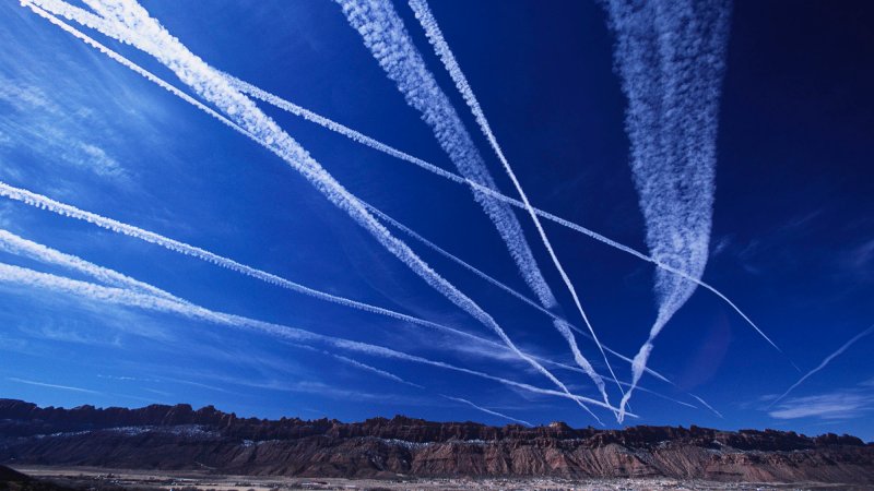 Contrail clouds from passing jet planes streak the sky over the Utah desert.