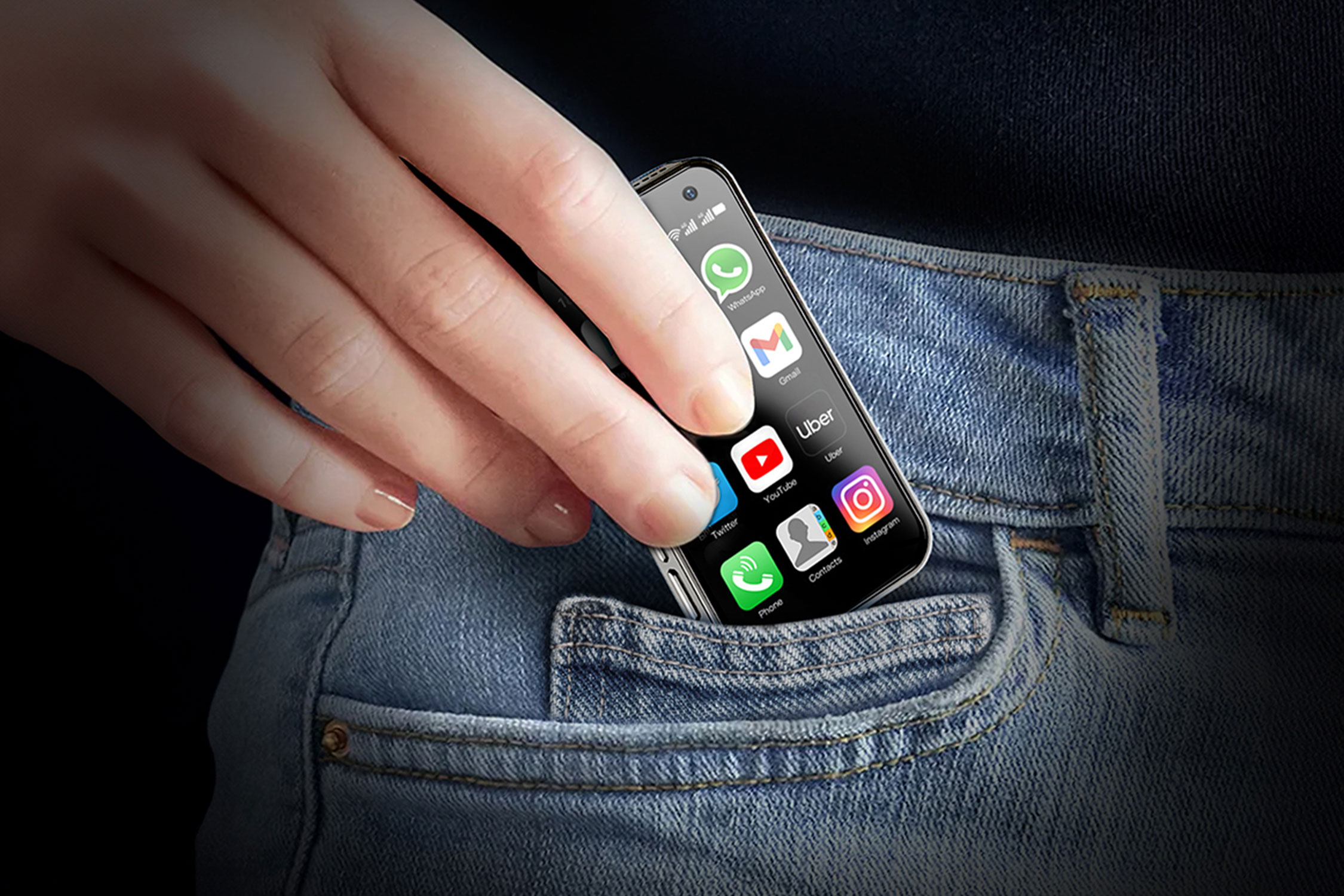 A person putting a small phone into a jeans pocket.