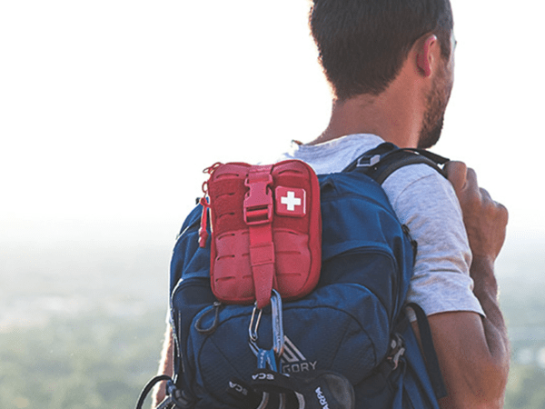 A person hiking with a first aid survival kit.