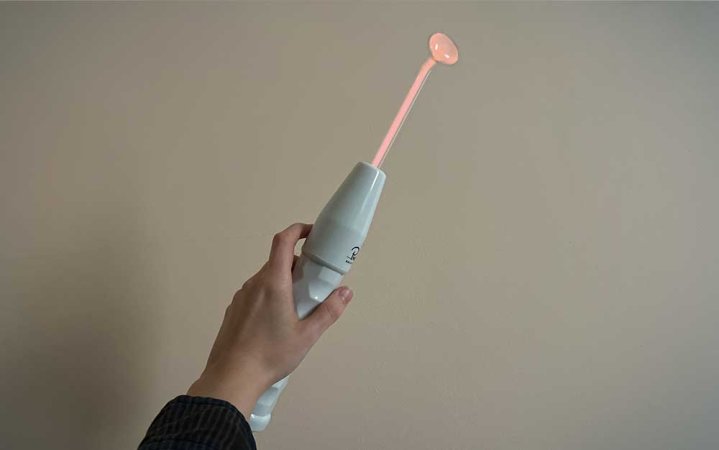  A person holding a NuDerma high frequency wand with neon