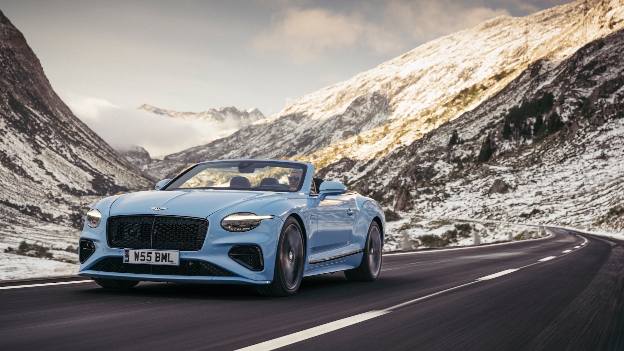 a blue convertible on a mountain road