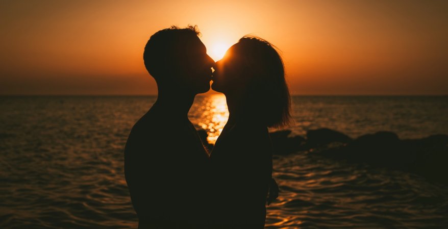 Silhouette of a loving couple hugging and kissing at sunset on the beach.