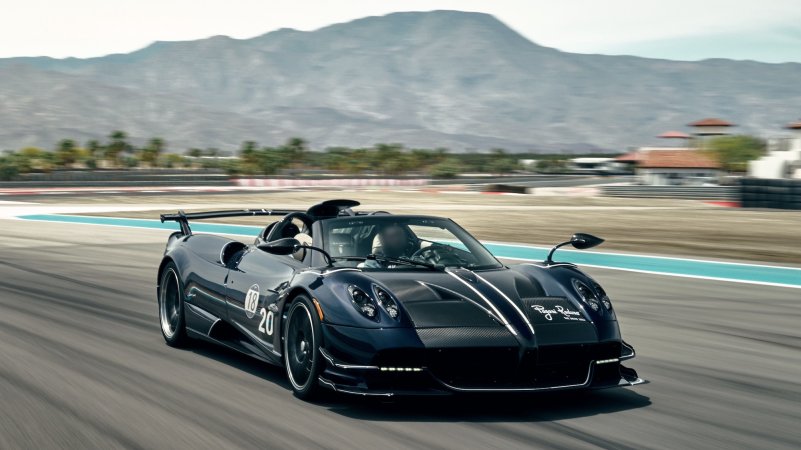 a black race car on a track in front of a hill