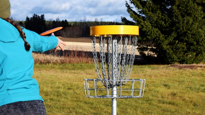 Woman throwing disc golf disc in park