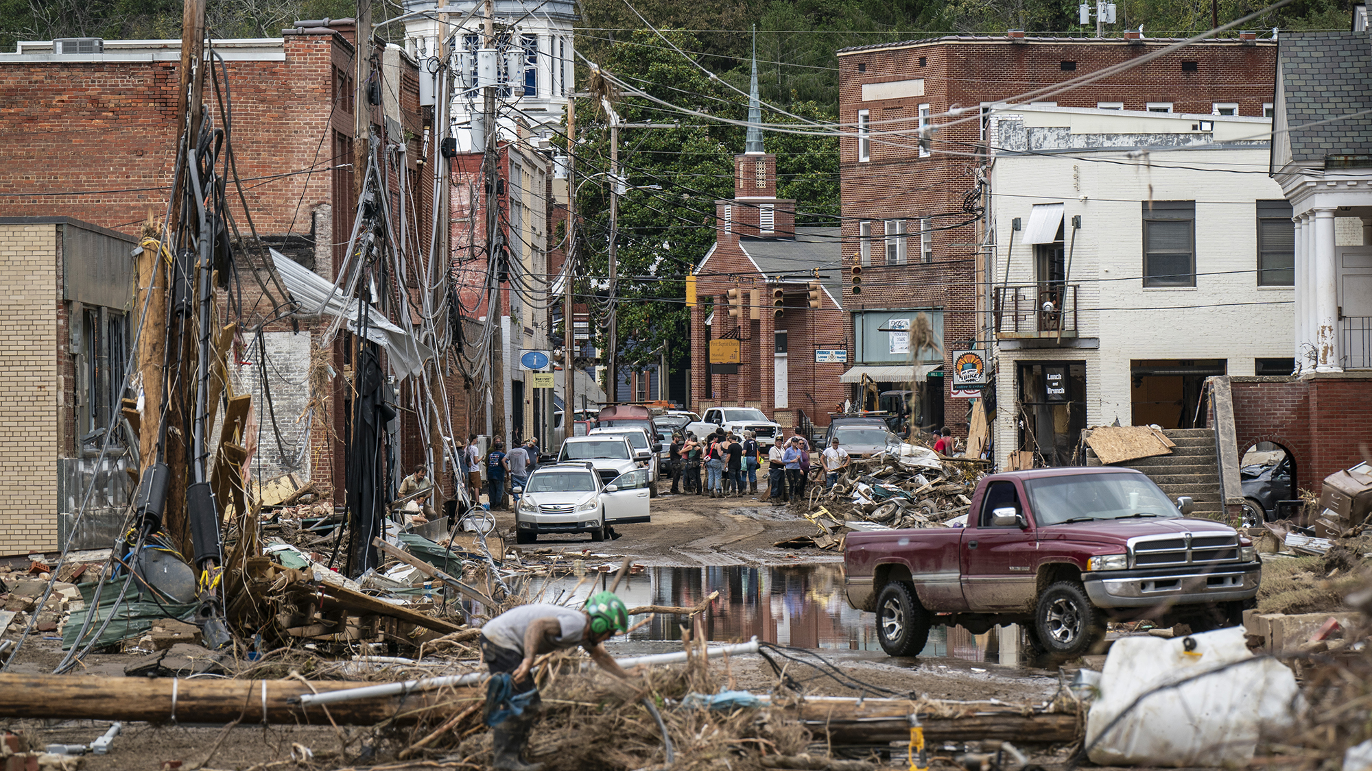 Workers, community members, and business owners clean up debris in the aftermath of Hurricane Helene in Marshall, North Carolina on Monday, Sept. 30, 2024.