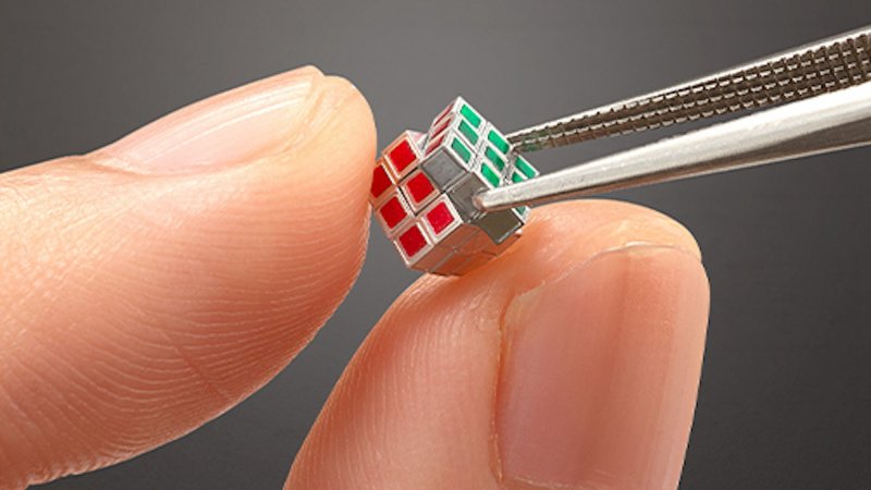 Close up of smallest Rubik's Cube being solved with tweezers