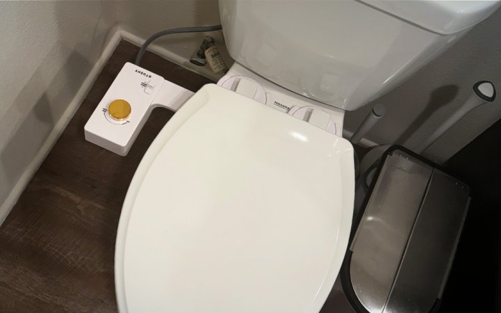  A white Tushy Classic 3.0 bidet attachment with a bamboo knob displayed on a closed toilet