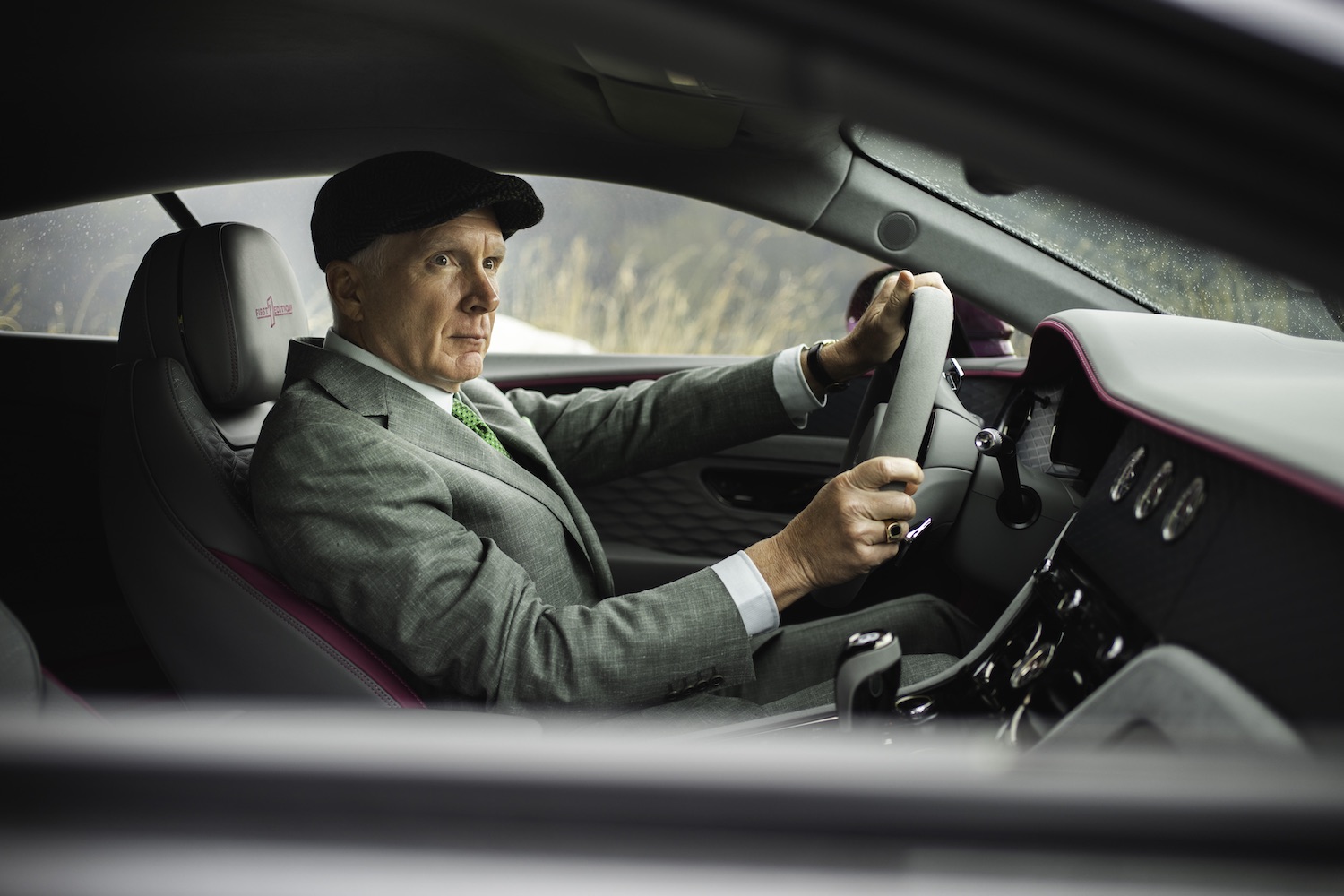 man in suit and hat driving car