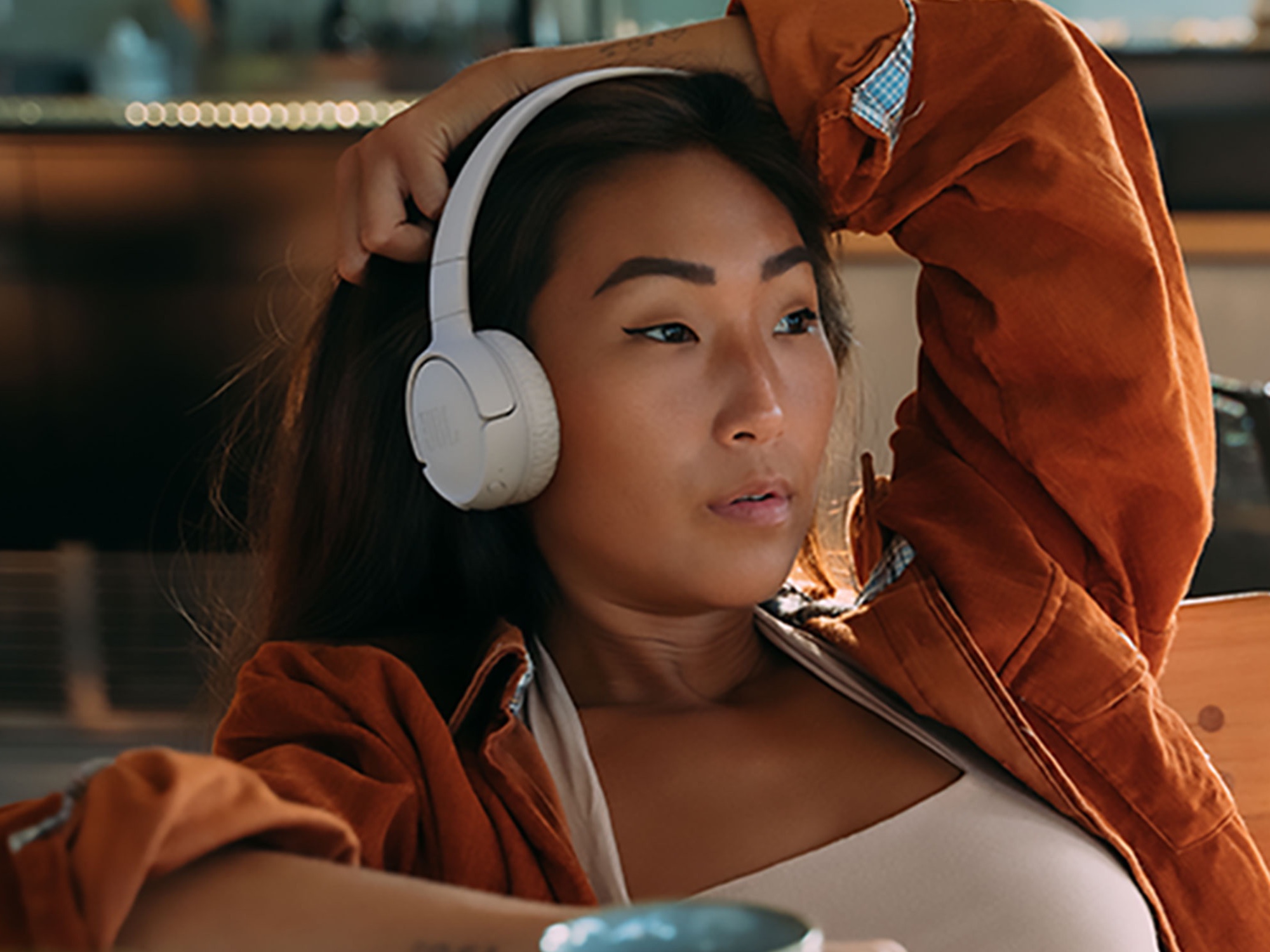 A person listening to music on JBL over-ear headphones.