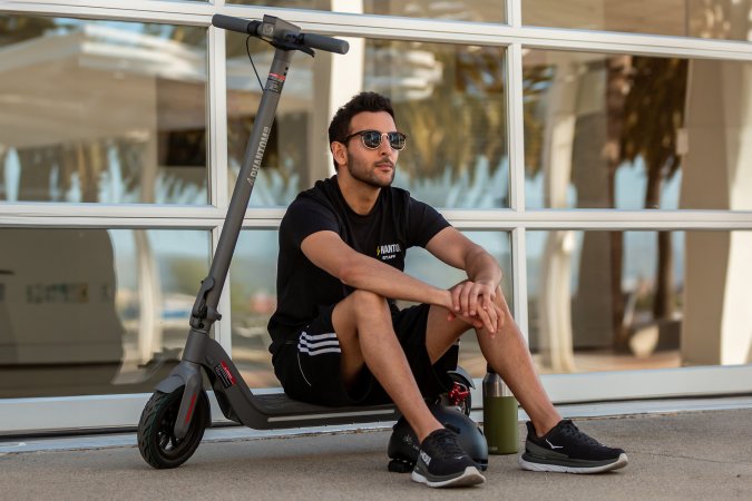 A person with a Phantom A9 Standing e-Scooter sitting on a sidewalk.