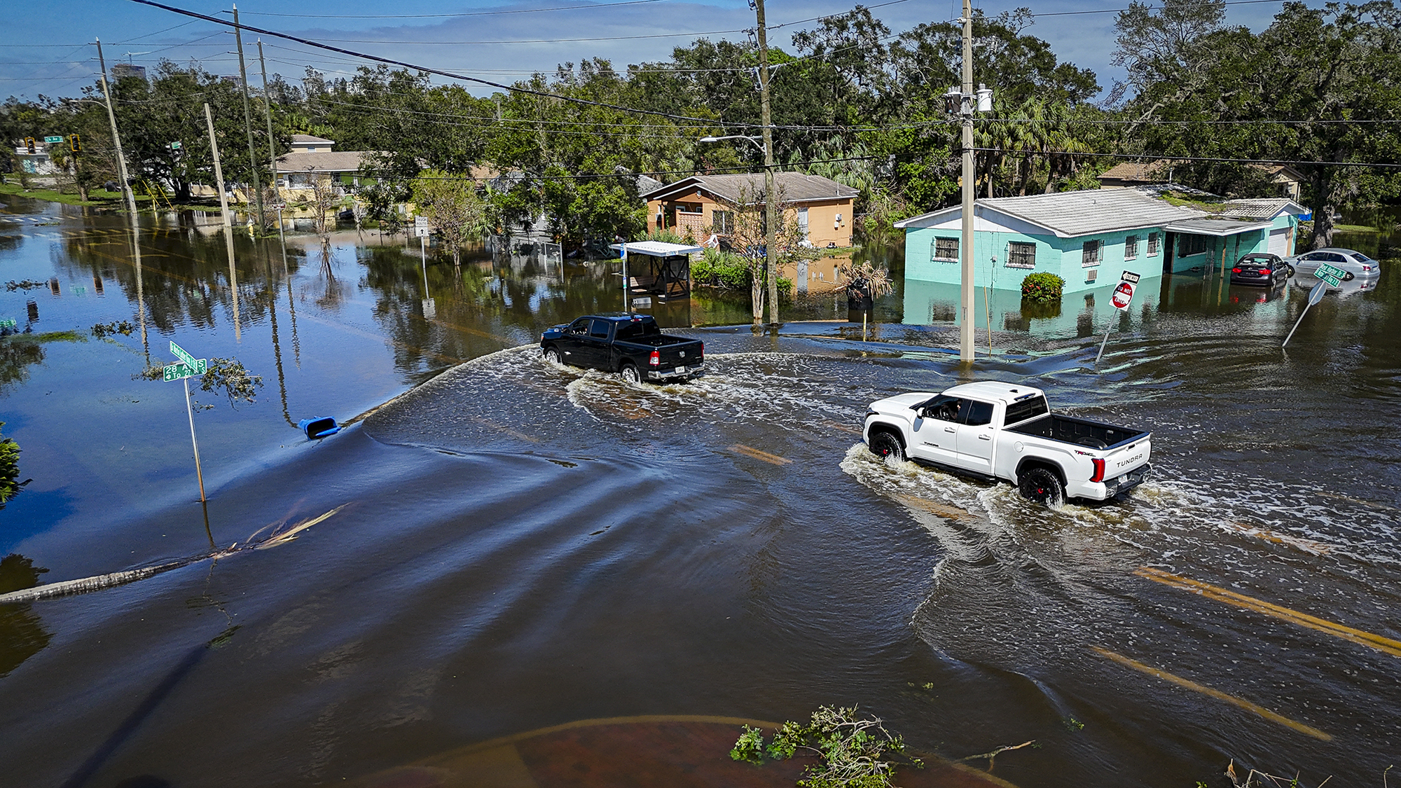 Vehicles drive through flood waters in the aftermath of Hurricane Milton in Lake Maggiore, Florida, on October 10, 2024