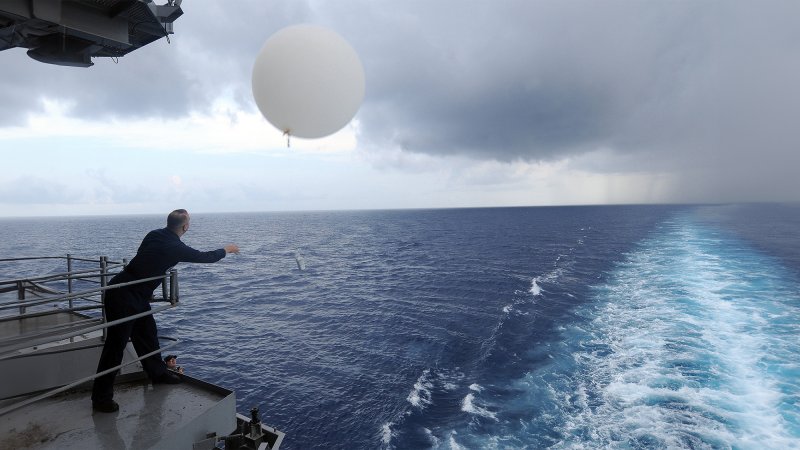 A US Navy officer releases a weather balloon over the Atlantic Ocean in 2009. Today, the United States launches around 76,600 balloons annually to gather high-altitude weather data on air temperature, pressure, and humidity.