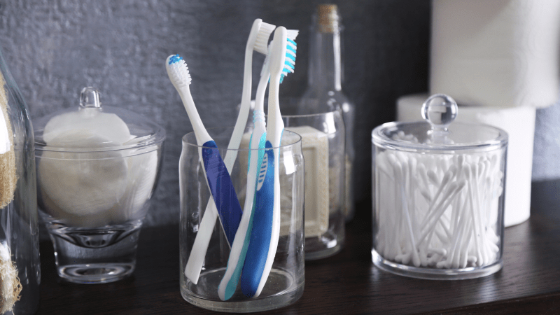 five toothbrushes in a cup on a bathroom sink