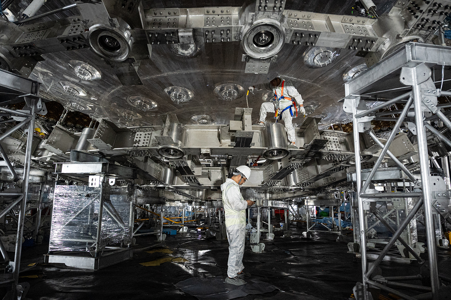 This photo taken during a media tour on October 11, 2024 shows workers working on the stainless steel structure of the neutrino detector. Credit: JADE GAO/AFP via Getty Images
