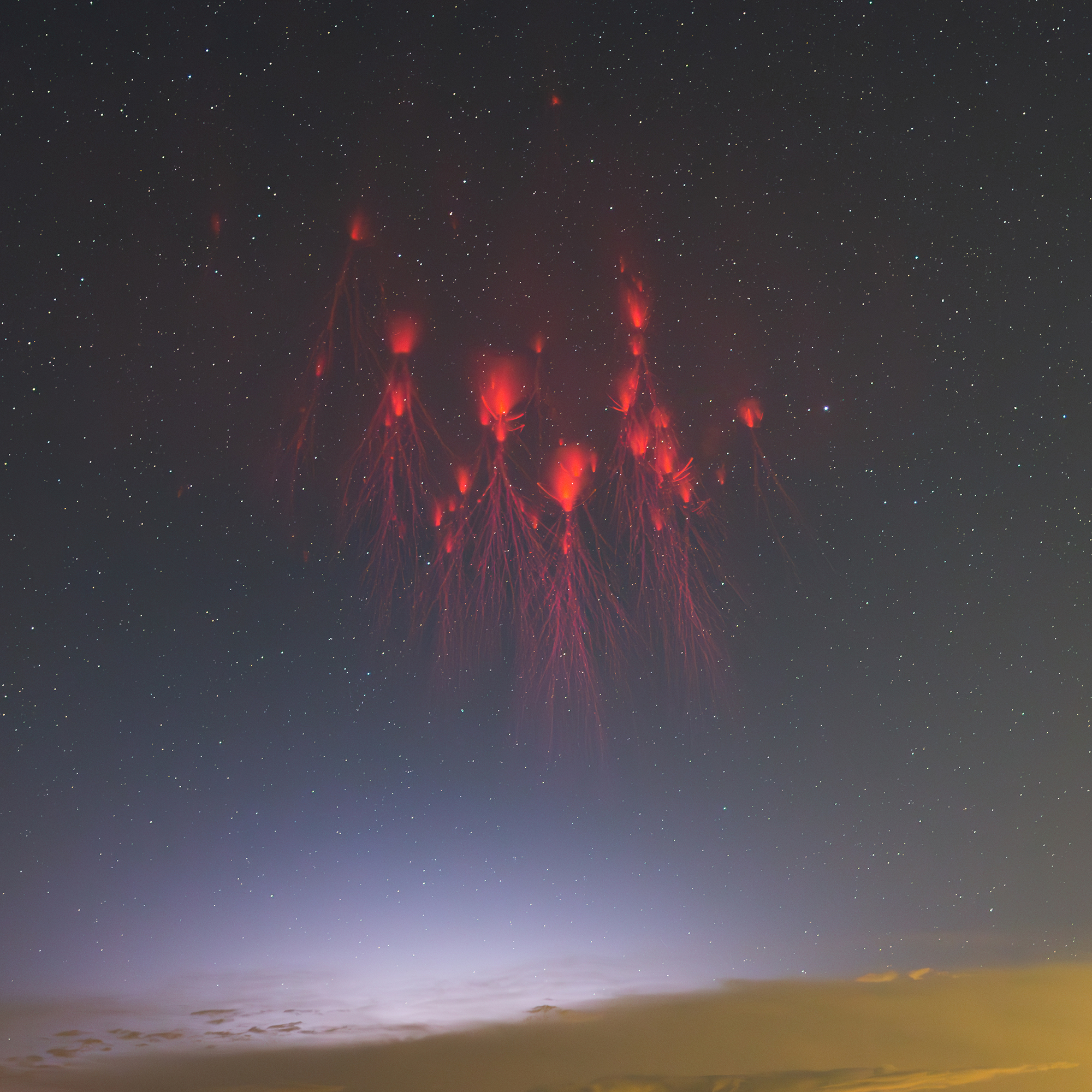 red bursts of color in the night's sky with storm clouds below