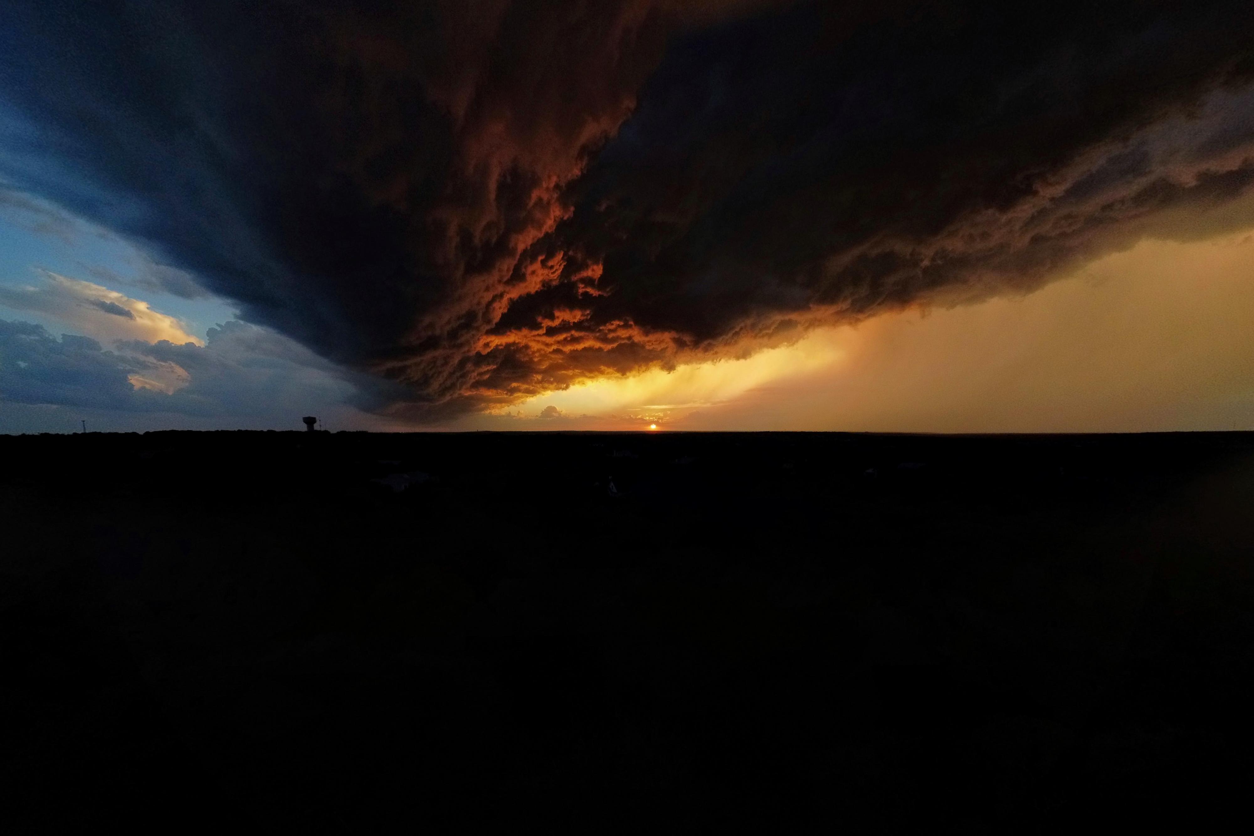 triangular-shaped storm clouds on the horizon as the sun sets