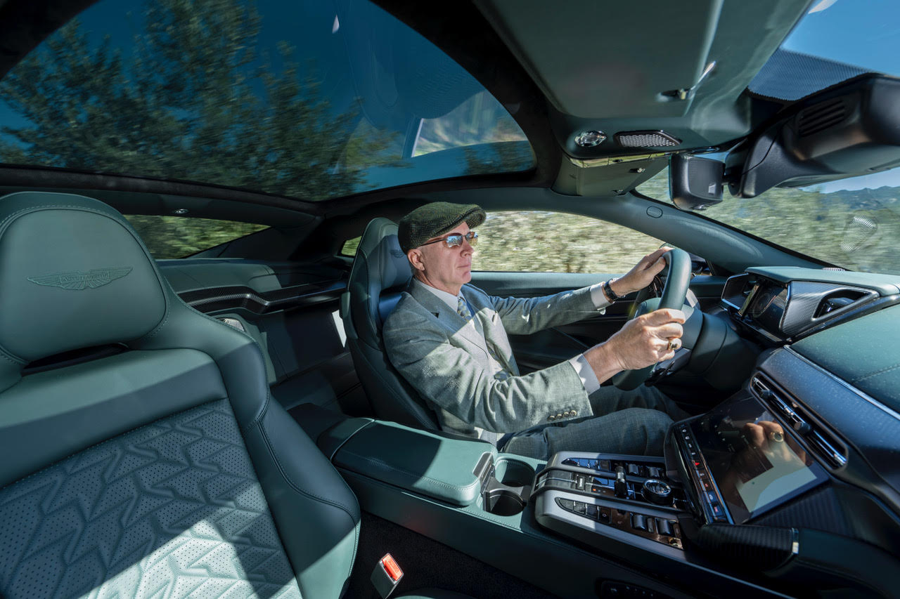 a man in a hat behind the wheel of a two-seater car