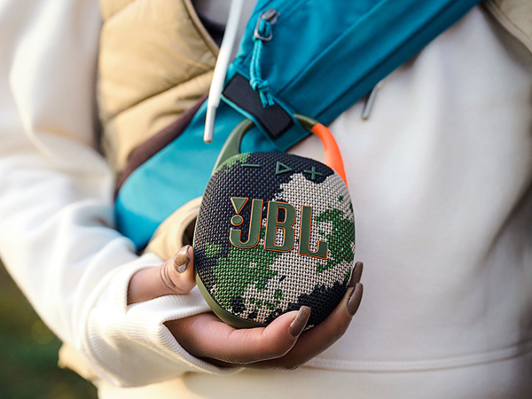 A person holding a JBL personal speaker.