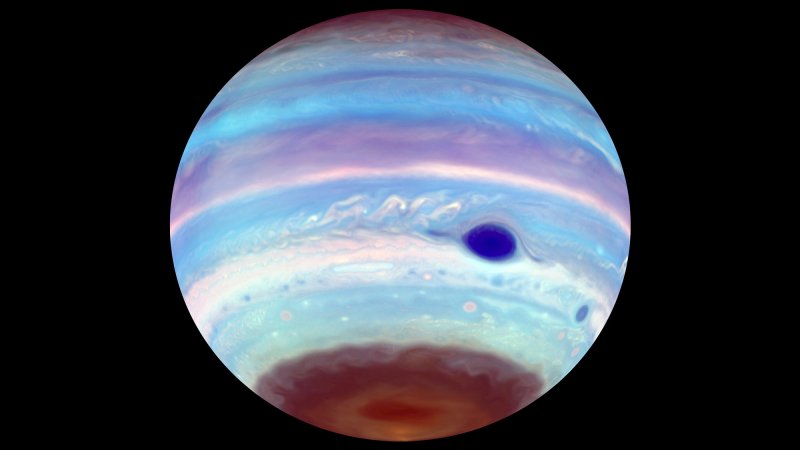 An artificially colored view of Jupiter as seen in ultraviolet light. In addition to the Great Red Spot, which appears blue, another oval feature can be seen in the brown haze at Jupiter's south pole. The oval, an area of concentrated haze, is possibly the result of mixing generated by a vortex higher up in the planet's ionosphere. These dark UV ovals also appear periodically at the north pole, though less often.