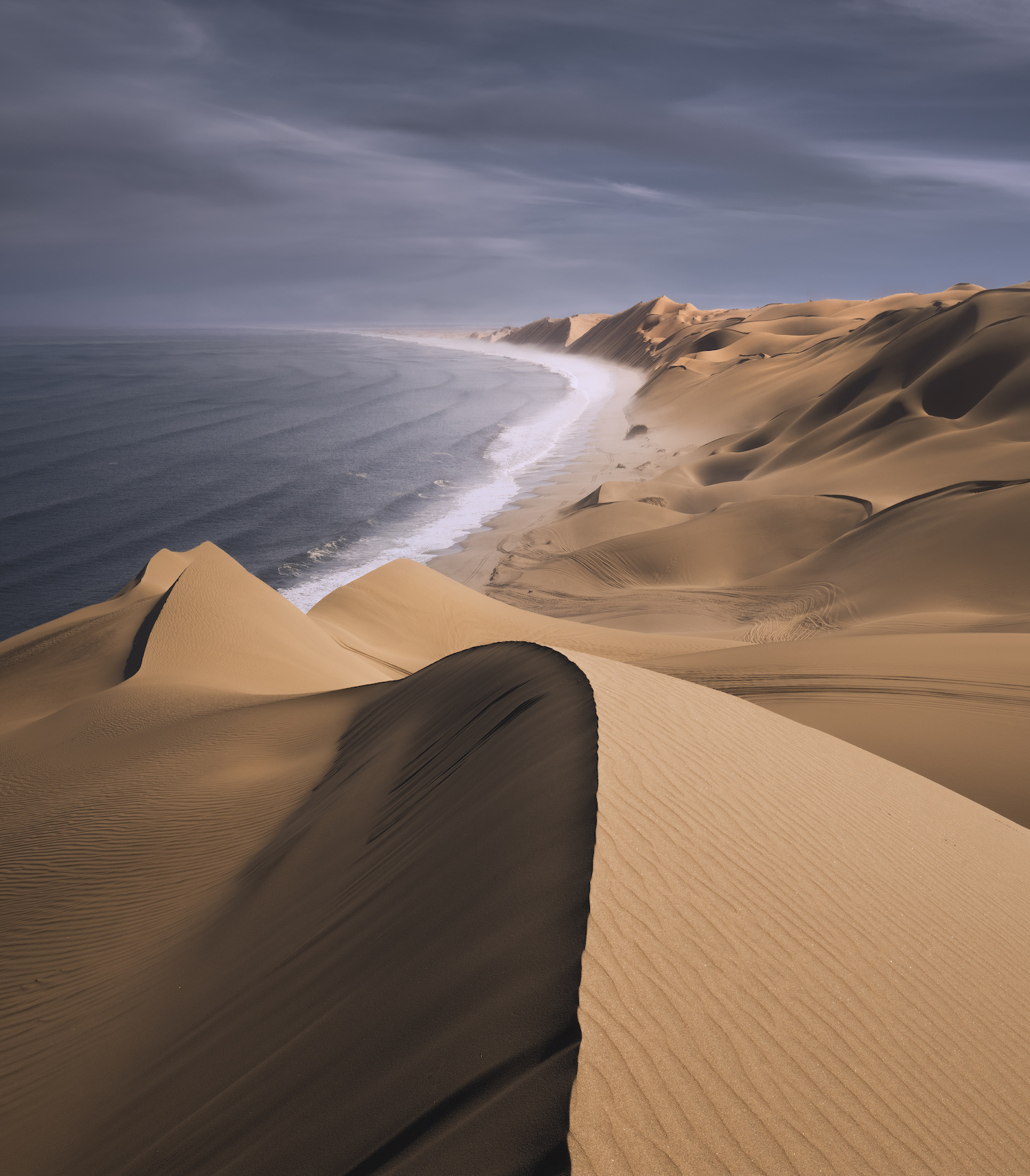 large side dunes saddle directly to the sea as the waves crash