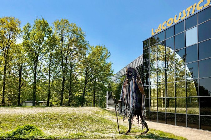 A metal statue of L-Acoustics company mascot Bob standing in front of the Marcoussis HQ