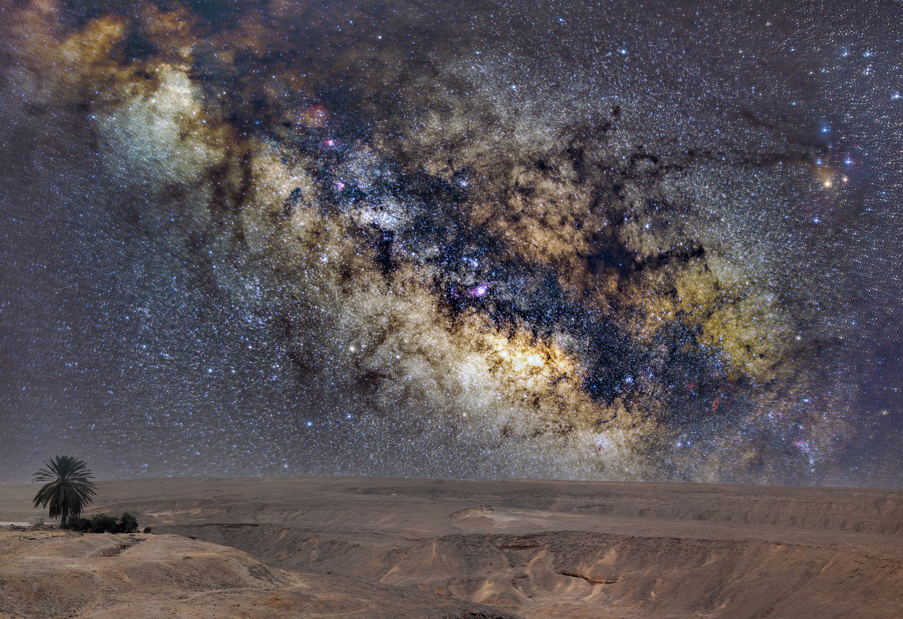 the desert with the milky way stretched across the sky