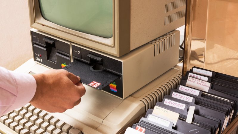 Aged Apple computer and hand insert floppy inside