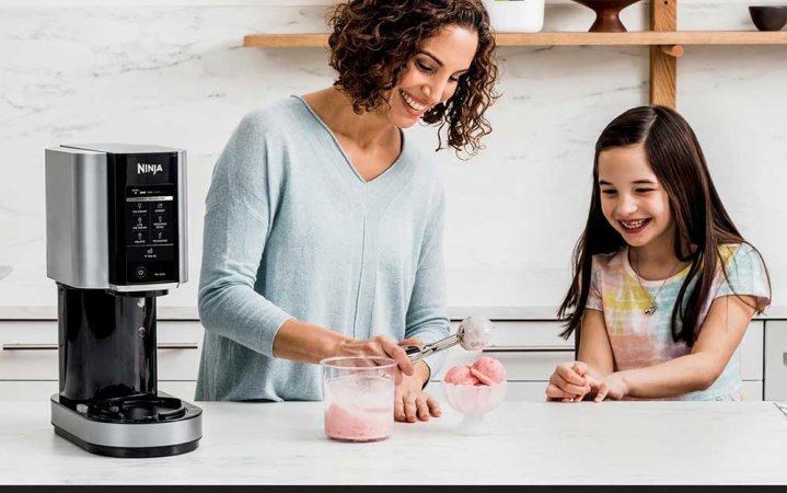 A mother and daughter making ice cream in the kitchen using a Ninja Creami