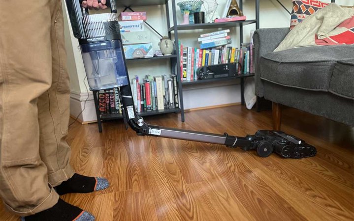 A person using the Shark Stratos Vacuum to clean under a couch.