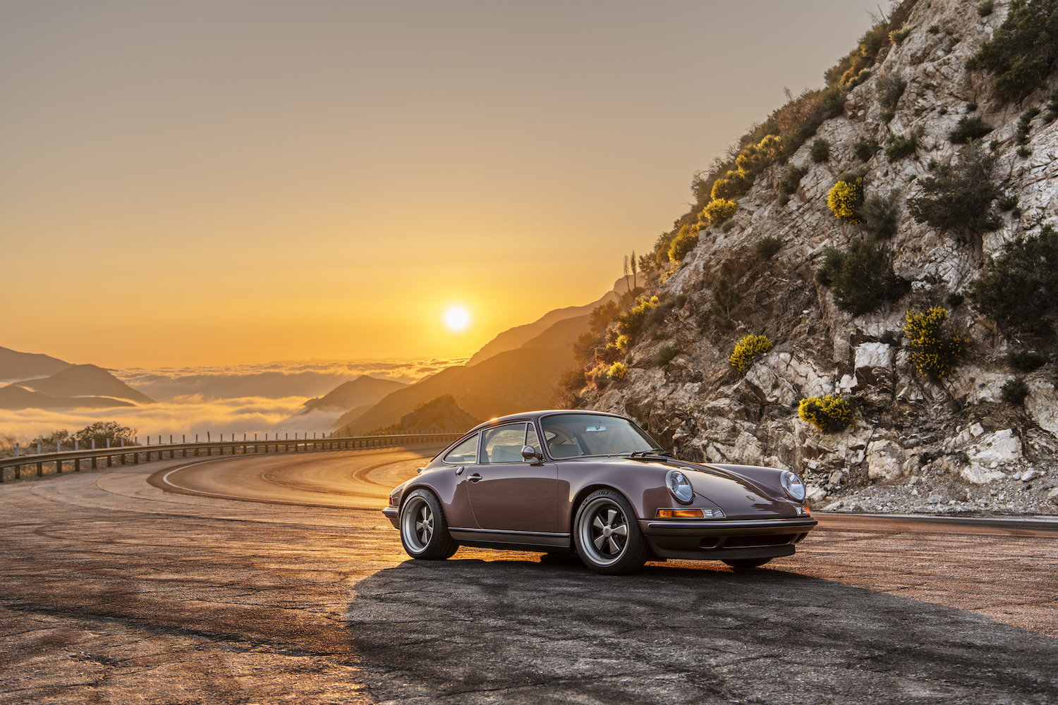 restored sports car on mountain road at sunset