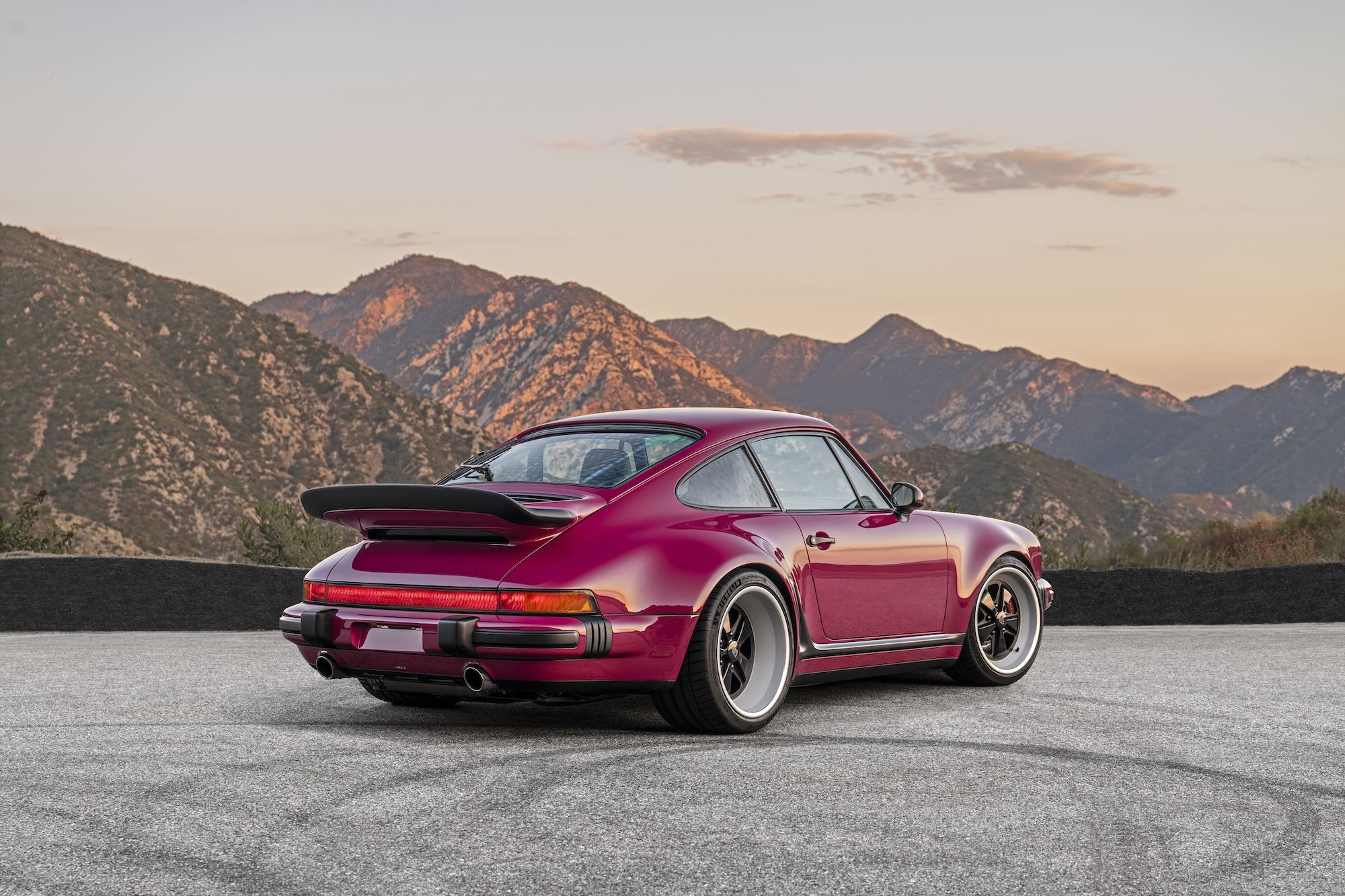 a magenta sports car parked in the mountains