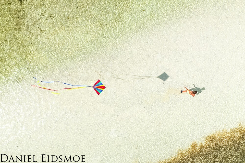 a woman walks with a kite. photograph is taken from above