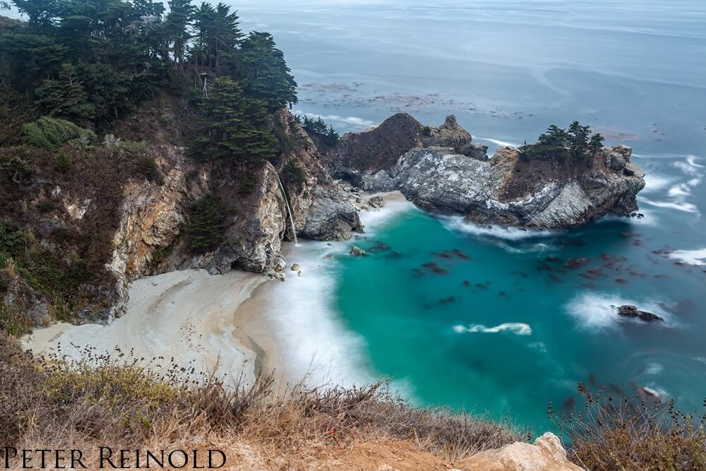 an isolated beach with cliffs and trees